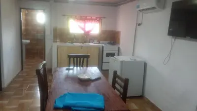 a kitchen with a wooden table and a refrigerator at Cabaña Aguaribay in Villa Anizacate
