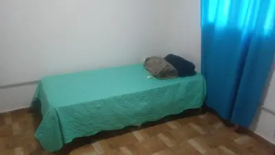 a room with a green bed with blue curtains at Cabaña Aguaribay in Villa Anizacate