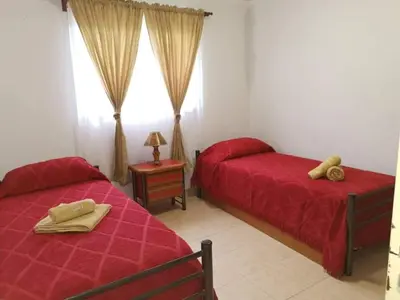 a bedroom with two beds with red sheets and a window at mi casita en tanti, casa 25 in Tanti