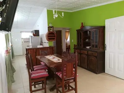 a kitchen with green walls and a wooden table and chairs at mi casita en tanti, casa 25 in Tanti