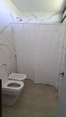 a bathroom with a toilet and a white tiled wall at Cabañas Chirivita Atos Pampa in Atos Pampa