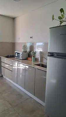 a kitchen with white cabinets and a white refrigerator at Cabañas Chirivita Atos Pampa in Atos Pampa