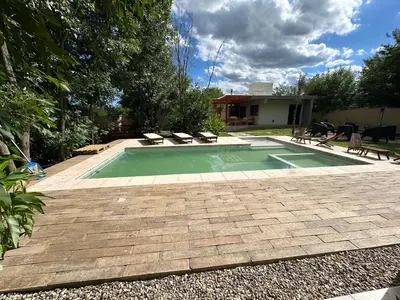 a swimming pool with two chairs and a house at Aires- Casas de campo in Villa Carlos Paz