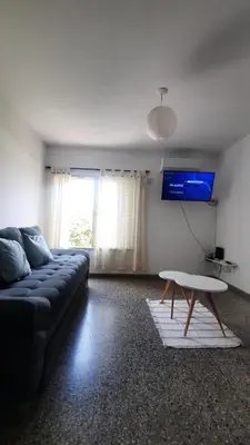 a living room with a couch and a table and a tv at Temporario Nebwery Villa Carlos Paz in Villa Carlos Paz