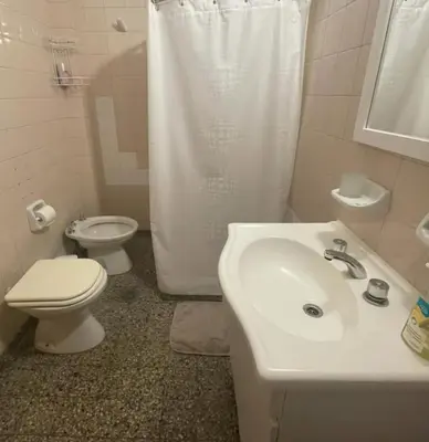 a white bathroom with a toilet and a sink at Temporario Nebwery Villa Carlos Paz in Villa Carlos Paz
