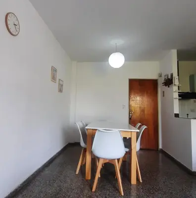 a dining room with a table and chairs and a clock at Temporario Nebwery Villa Carlos Paz in Villa Carlos Paz