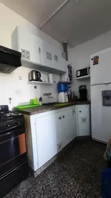 a kitchen with white cabinets and a black stove at Temporario Nebwery Villa Carlos Paz in Villa Carlos Paz