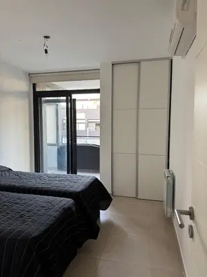 a bedroom with a bed and sliding glass doors at Dpto a estrenar Villa Carlos Paz frente a la costanera in Villa Carlos Paz