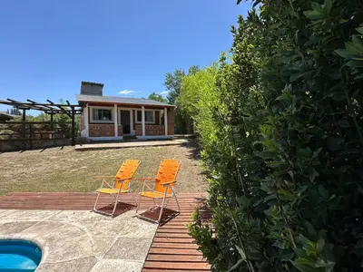 two chairs sitting on a patio next to a house at La Casa de Aromas del Valle in Santa Rosa de Calamuchita
