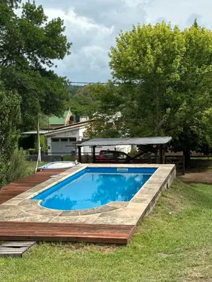 a swimming pool in a yard with a wooden deck at La Casa de Aromas del Valle in Santa Rosa de Calamuchita