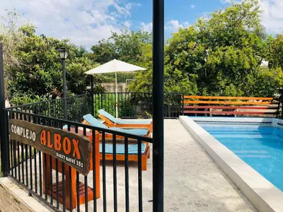 a pool with chairs and an umbrella next to a fence at Complejo Albox in Villa Carlos Paz