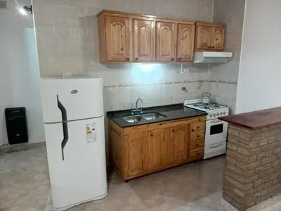 a kitchen with a white refrigerator and wooden cabinets at Complejo Albox in Villa Carlos Paz