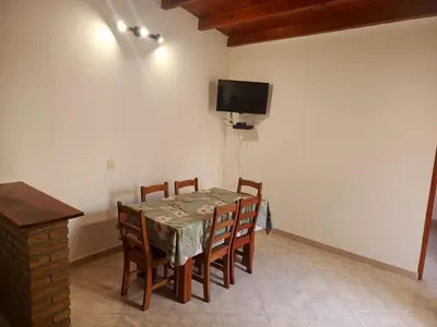 a dining room table with chairs and a television on the wall at Complejo Albox in Villa Carlos Paz