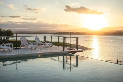 a pool with chairs and the sun setting over the water at PUEBLO CHICO - casas de lago in Villa Ciudad de America