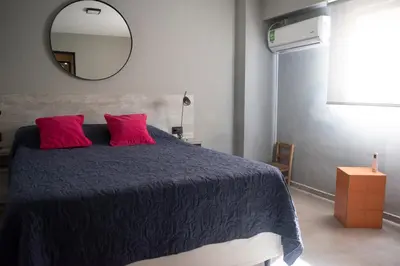 a bedroom with a bed with red pillows and a mirror at Departamento Córdoba Centro in Cordoba