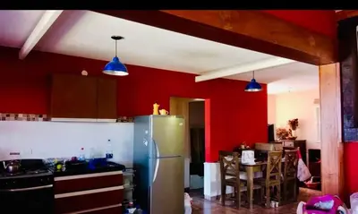 a kitchen with red walls and a stainless steel refrigerator at Alquilo casa totalmente equipada con pileta y vista a las Sierras in Tanti
