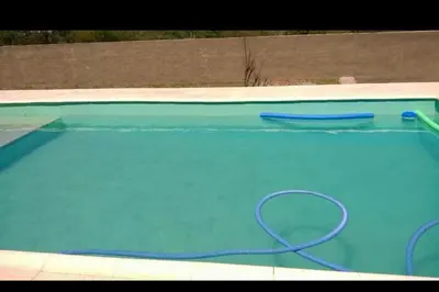 a swimming pool with a hose in the water at Alquilo casa totalmente equipada con pileta y vista a las Sierras in Tanti