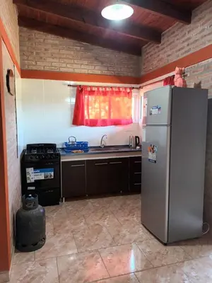 a kitchen with a stainless steel refrigerator and a window at Cabañas Gael in Barrio Parque El Corcovado