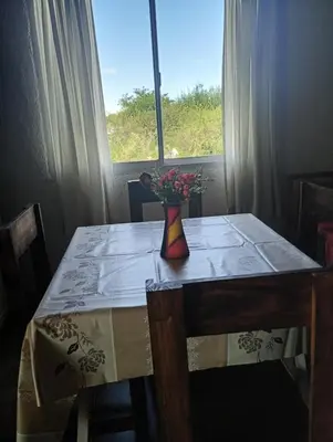 a table with a vase of flowers on it with a window at Casita feliz in Villa del Dique