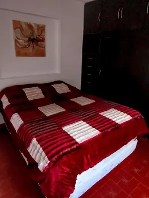 a bed with a red and white quilt on it at El Paraiso 1 in Villa Carlos Paz