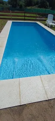 a large blue swimming pool in a yard at las huertitas de milele in La Porteña