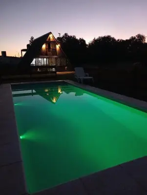 a green pool with a house in the background at las huertitas de milele in La Porteña