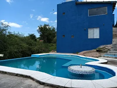 a swimming pool in front of a blue building at Los Talitas in Villa Parque Siquiman