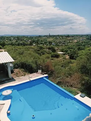 a blue swimming pool with a view of a field at Los Talitas in Villa Parque Siquiman