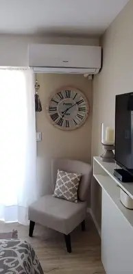 a clock hanging on a wall with a chair at edificio acuario 1 in Villa Carlos Paz