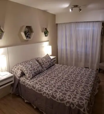 a bedroom with a bed and two lamps and a window at edificio acuario 1 in Villa Carlos Paz