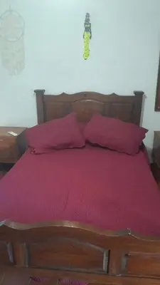 a bedroom with a wooden bed with red sheets and pillows at JM brochero in Villa Cura Brochero