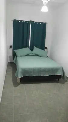 a bedroom with a green bed with a blue curtain at JM brochero in Villa Cura Brochero