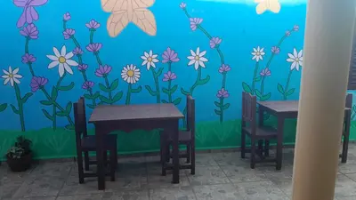 a dining room with two tables and flowers on the wall at JM brochero in Villa Cura Brochero