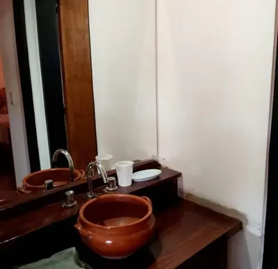a bathroom with a wooden sink and a copper bowl at Casa y cabañas Sara in Villa Rumipal