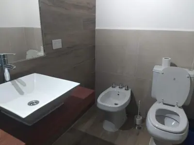 a bathroom with a white toilet and a sink at Casa y cabañas Sara in Villa Rumipal
