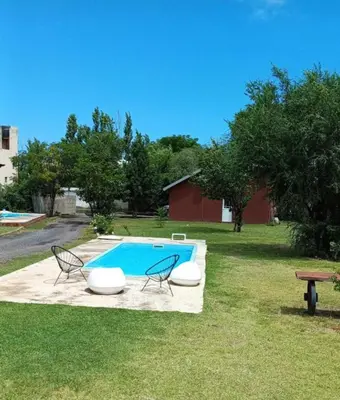 a swimming pool with two chairs and a table at Casa y cabañas Sara in Villa Rumipal