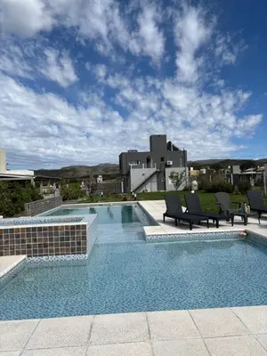 a swimming pool with two chairs and a building at En Gracia, tu casa de Montaña in Alta Gracia