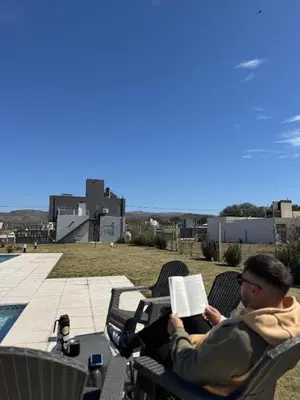 a man sitting in a chair reading a book at En Gracia, tu casa de Montaña in Alta Gracia