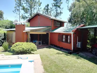 a red house with a pool in front of it at Claro de Luna in Los Reartes