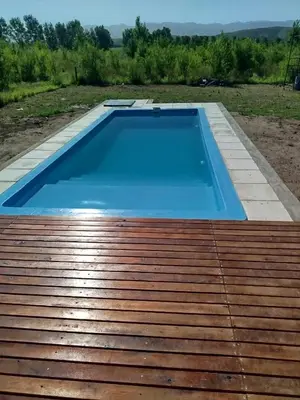 a large blue swimming pool on top of a wooden deck at Casa a estrenar En Trapiche - Pileta privada in Trapiche