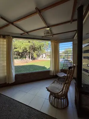 a screened in porch with a chair and a window at Complejo Villa Lago in Villa Carlos Paz