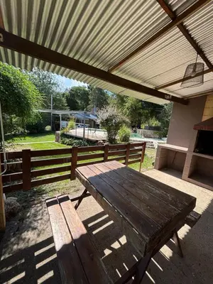 a wooden picnic table under awning on a patio at Complejo Villa Lago in Villa Carlos Paz