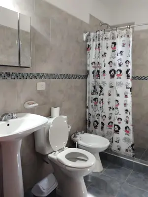 a bathroom with a toilet and a sink and a shower curtain at Berna in Carpintería