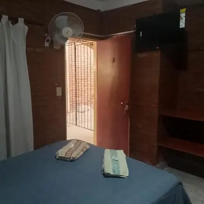 a room with a bed with a blue blanket and a window at Hostería Huanel in Villa Cura Brochero