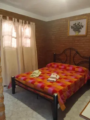 a bedroom with a bed with a colorful blanket at Hostería Huanel in Villa Cura Brochero