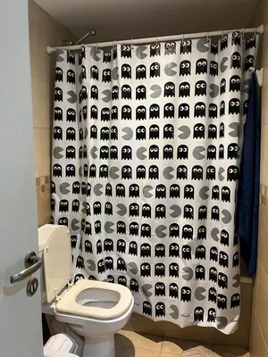 a bathroom with a toilet with a black and white shower curtain at Confortable departamento en el centro de la ciudad in Cordoba