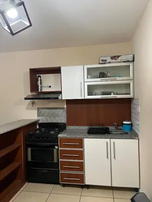 a small kitchen with a stove and white cabinets at Confortable departamento en el centro de la ciudad in Cordoba
