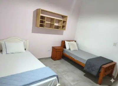 a room with two beds and a chair in it at Casa centrica in Villa Carlos Paz