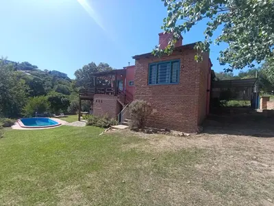 a brick house with a pool in the yard at Casa Mirta in Villa Carlos Paz