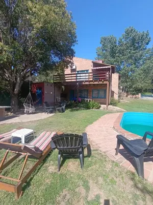 a backyard with a pool and two chairs and a house at Casa Mirta in Villa Carlos Paz